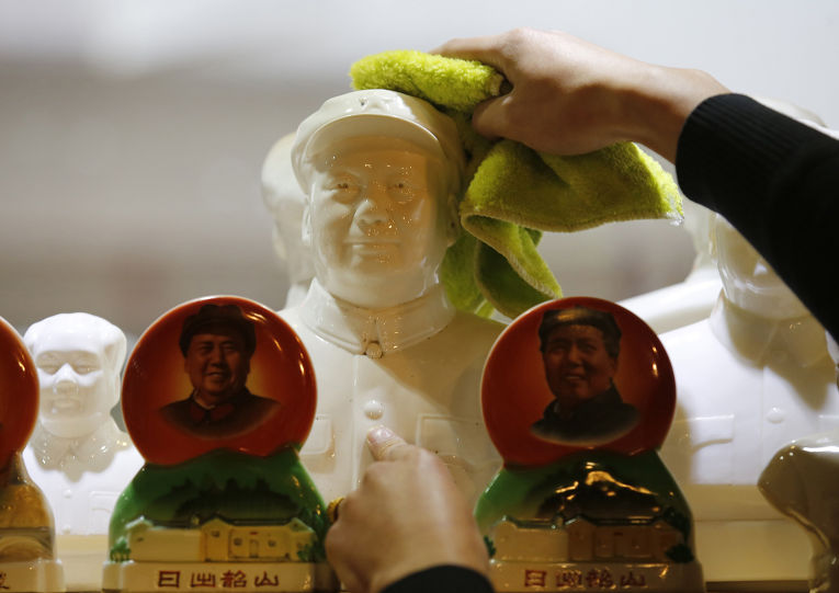 Служащий вытирает пыль с бюста Мао Цзедуна в антикварном магазине в Пекине