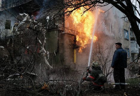 Пожарный тушит пожар в жилом доме, возникший в результате обстрела Донецка украинскими силовиками