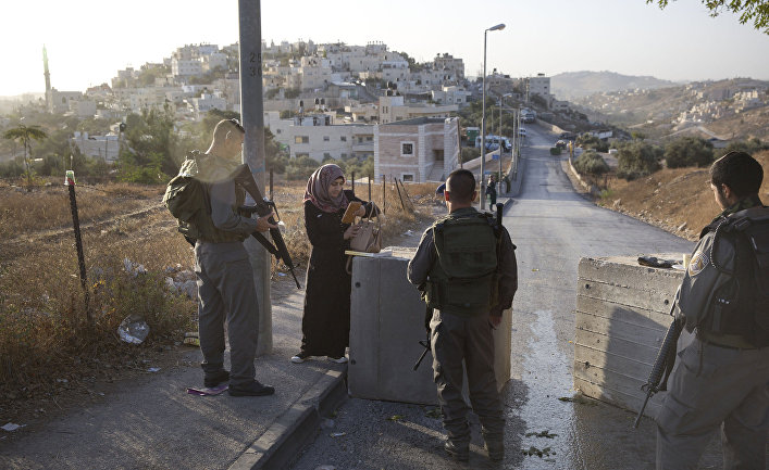 Израильские полицейские проверяют документы у палестинки рядом с бетонными блоками, установленными на востоке Иерусалима