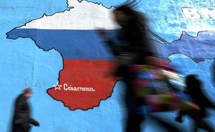 Прохожие у нарисованной на стене карты Крыма в цветах российского флага в Москве