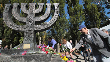 Люди возлагают цветы к памятнику в Национальном историкомемориальном заповеднике "Бабий Яр"