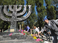 Люди возлагают цветы к памятнику в Национальном историкомемориальном заповеднике "Бабий Яр"