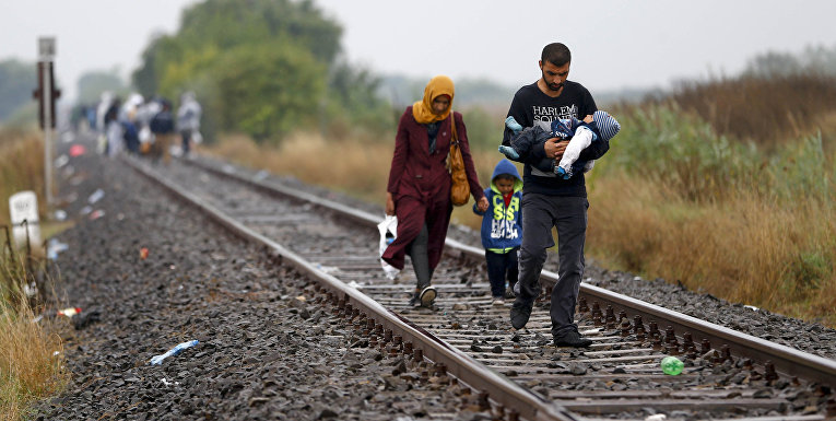 Семья беженцев идет в направлении временного лагеря на юге Венгрии