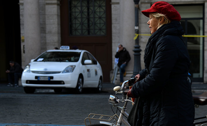 Женщина пользуется велосипедом во время акции протеста таксистов в центре Рима