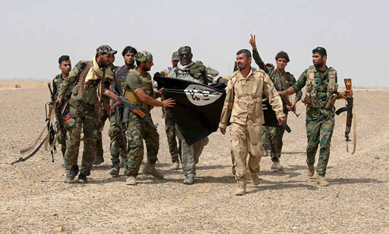 Бойцы иракских полувоенных формирований с сорванным в Нибаи флагом Исламского государства