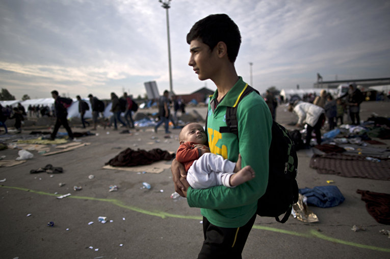 Беженец из Афганистна с 10-тимесячным племянником на руках после пересечения венгерско-австрийской границы