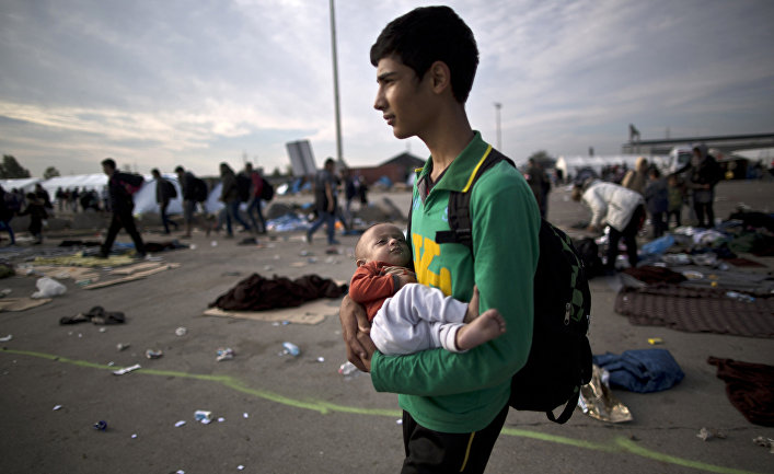 Беженец из Афганистна с 10-тимесячным племянником на руках после пересечения венгерско-австрийской границы