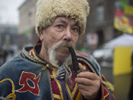 Мужчина в национальном костюме курит трубку на площади Независимости в Киеве Мужчина в национальном костюме курит трубку на площади Независимости в Киеве