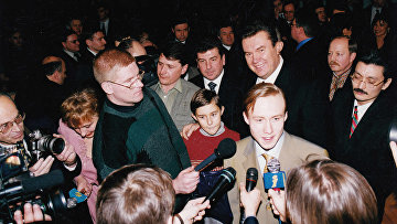 Руслан Пономарев дает интервью после ЧМ по шахматам 2002 года. Сзади в красном свитере стоит Сергей Карякин, рядом Виктор Янукович