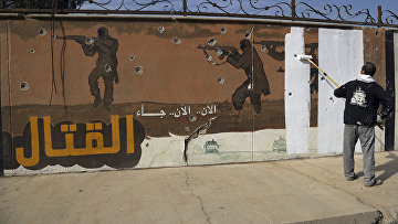 Волонтер закрашивает граффити, оставленное ИГИЛ в Мосуле