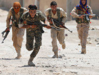 Курдские бойцы пробегают через улицу в Ракке 3 июля 2017
