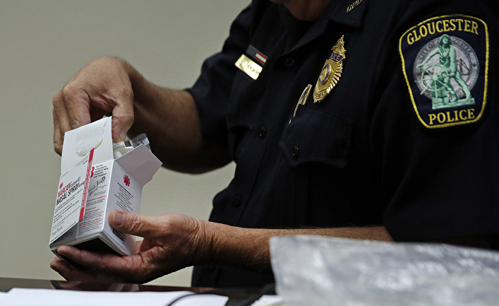 Полицейский открывает коробку с препаратом NARCAN, от передозировки наркотиками в полицейском участке в городе Глостер