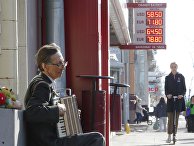 Уличный музыкант в Москве играет недалеко от вывески с курсом обмена валют