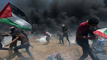 Палестинские демонстранты убегают от слезоточивого газа во время акции протеста против переноса посольства США в Иерусалим