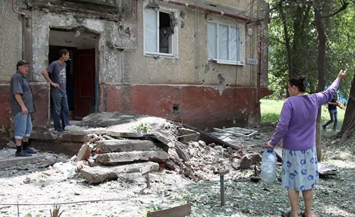 Жители во дворе жилого дома, пострадавшего в результате обстрела, в поселке Горловка Донецкой области