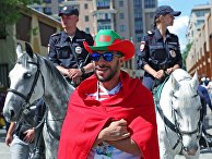 Болельщик сборной Марокко и конная полиция перед матчем Чемпионата мира по футболу между сборными Португалии и Марокко в Москве