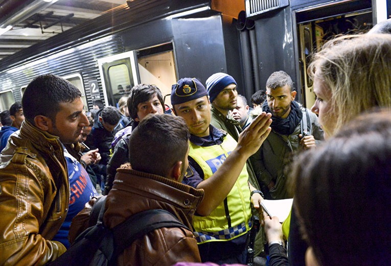 Сотрудник шведской полиции на вокзале в Стокгольме показывает дорогу мигрантам, прибывшим из Мальме