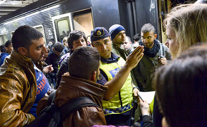 Сотрудник шведской полиции на вокзале в Стокгольме показывает дорогу мигрантам, прибывшим из Мальме