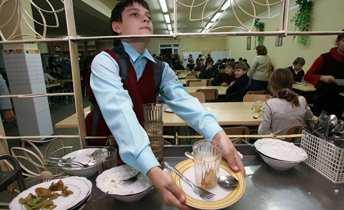 Школьник убирает за собой посуду в столовой