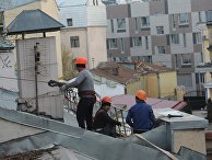 Рабочие-строители на крыше здания в Москве Рабочие-строители на крыше здания в Москве