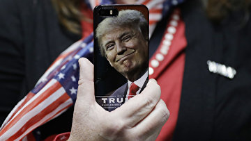 Женщина держит телефон с фотографией Дональда Трампа во время предвыборной кампании в США