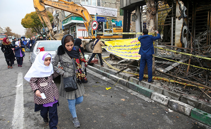 Люди в Тегеране идут мимо сгоревшего банка после протестов против повышения цен на топливо