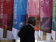 Мужчина проходит мимо баннеров Tokyo 2020