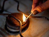 Женщина зажигает конфорку газовой плиты Женщина зажигает конфорку газовой плиты