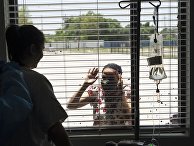 Пациентка общается через стекло с родственниками в госпитале United Memorial Medical Center в Хьюстоне, где проходят лечение больные с covid-19 Пациентка общается через стекло с родственниками в госпитале United Memorial Medical Center в Хьюстоне, где проходят лечение больные с covid-19