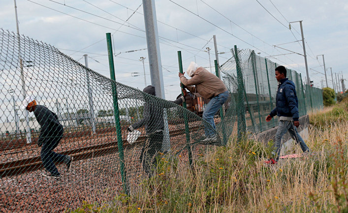 Мигранты перелезают через забор, чтобы пробраться к Евротуннелю
