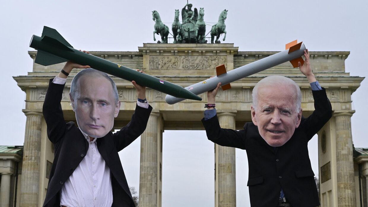 Активисты в масках Путина и Байдена позируют с макетами ядерных ракет перед Бранденбургскими воротами в Берлине