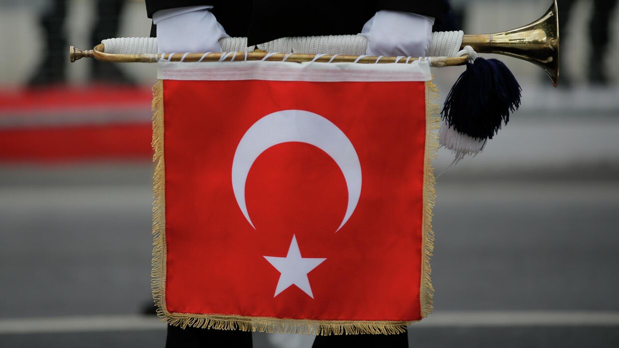 Турецкий военнослужащий держит трубу с турецким флагом