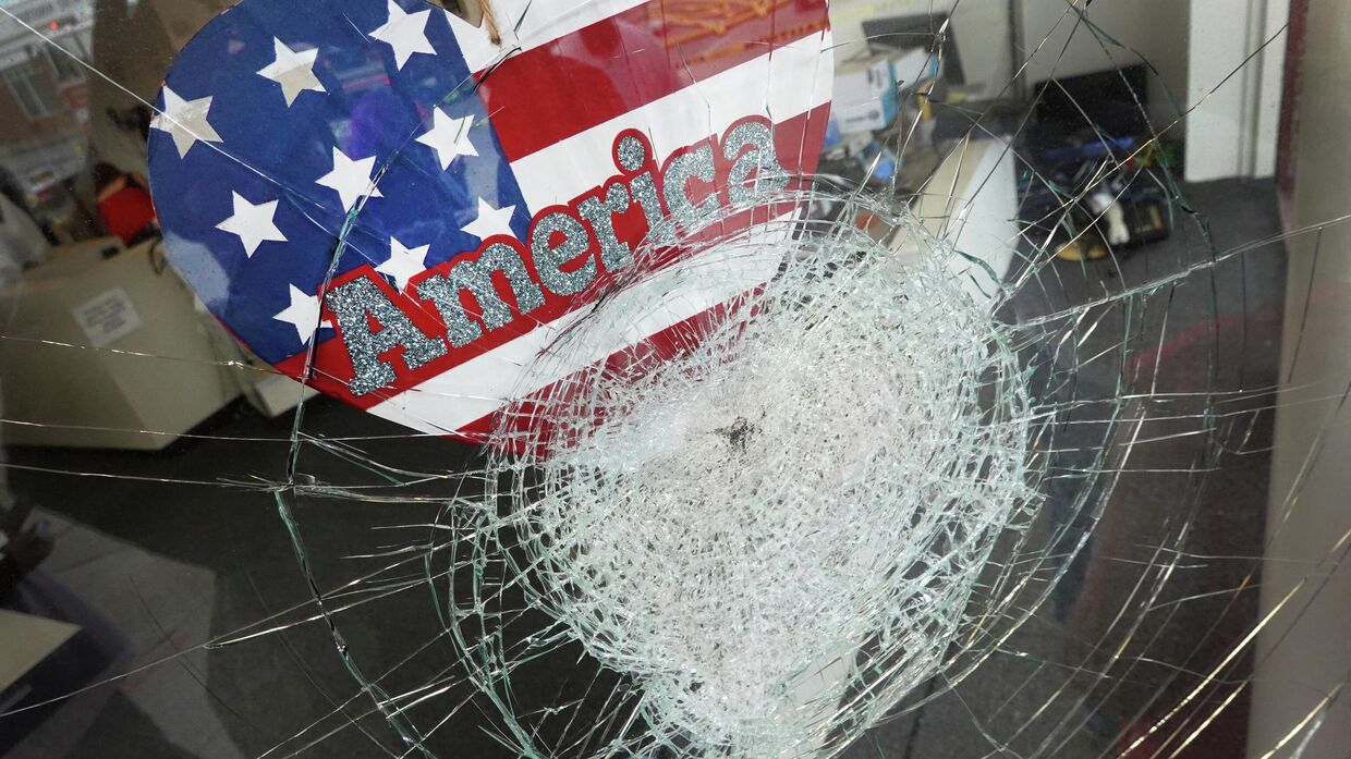 Наклейка с американским флагом на разбитой витрине магазина в Кеноше, штат Висконсин
