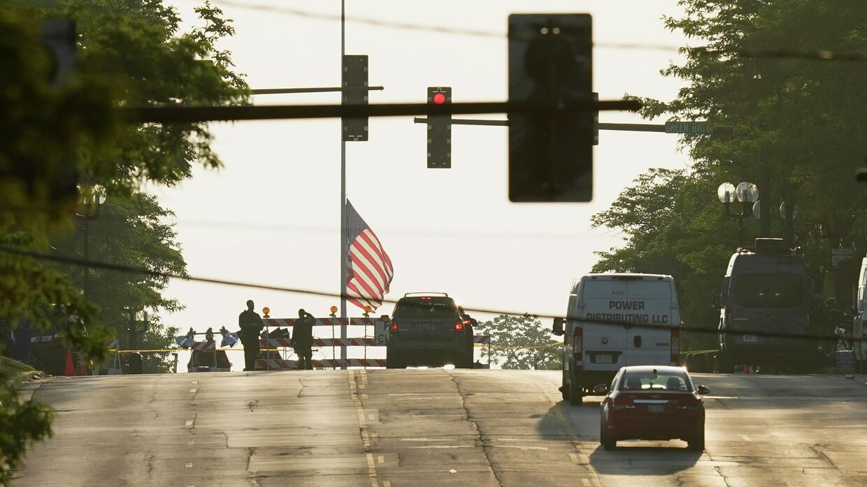 Полицейское оцепление и приспущенный американский флаг в Хайленд-парк, штат Иллинойс, после массовой стрельбы со смертельным исходом на параде в честь Дня независимости