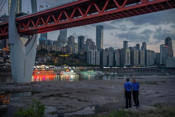 20 августа 2022 года. Сотрудники службы безопасности на обмелевшей реке Цзялин в городе Чунцин, Китай