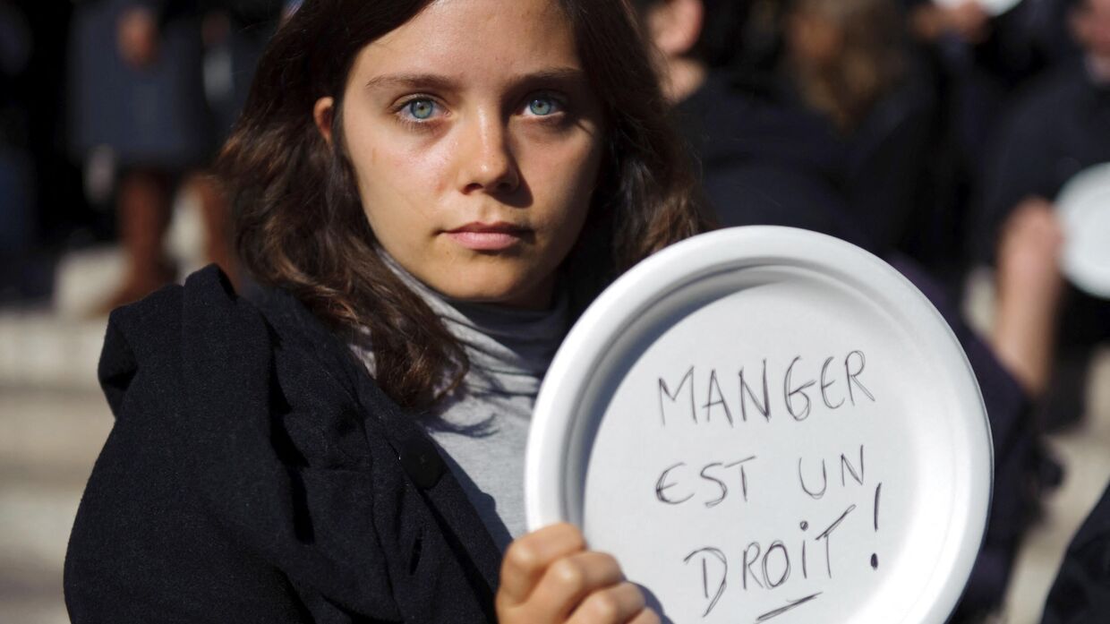 Девушка держит тарелку с лозунгом Питание - это право человека в Париже, Франция. Архивная фотография