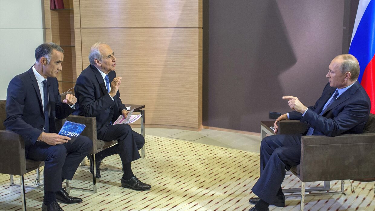 Президент России Владимир Путин отвечает французским журналистам Жилю Було и Жан-Пьеру Элькаббаху во время интервью французским СМИ TF1 и Europe 1 в Сочи 4 июня 2014 года.