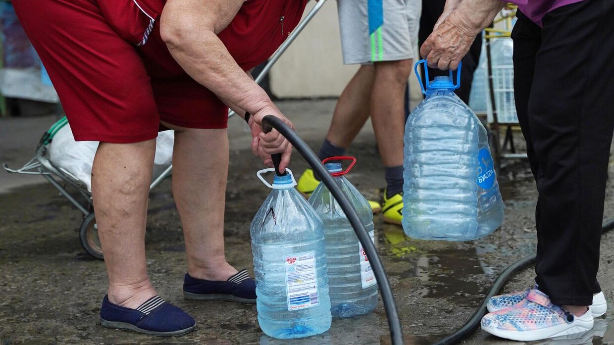 Местная жительница набирает питьевую воду возле одной из скважин в Рубежном
