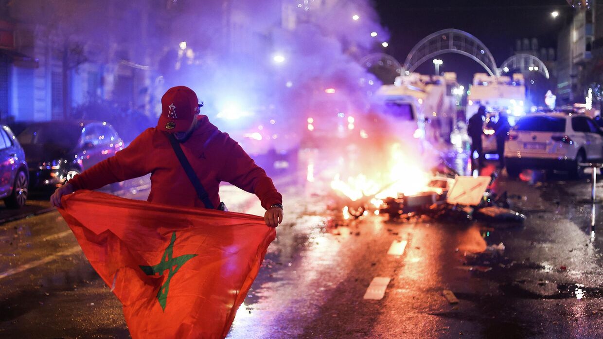 Болельщик держит марокканский флаг во время беспорядков в Брюсселе, Бельгия. 27 ноября 2022 года.