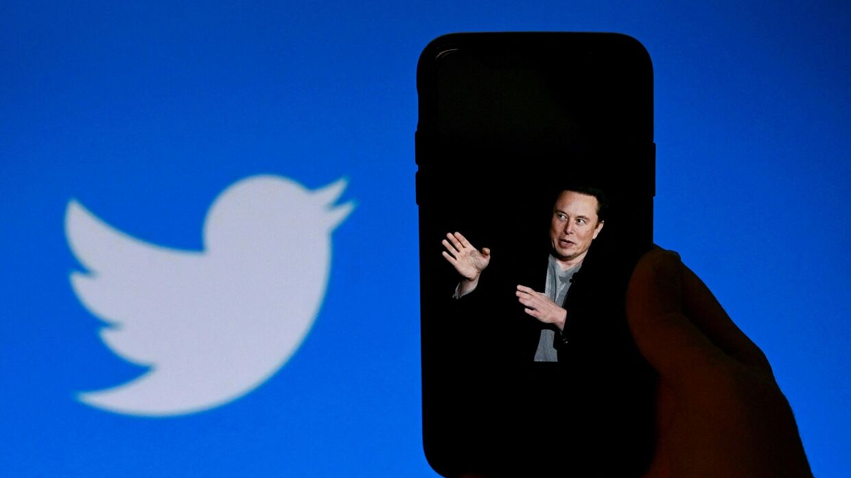 Фотография Илона Маска на экране смартфона и логотип Twitter