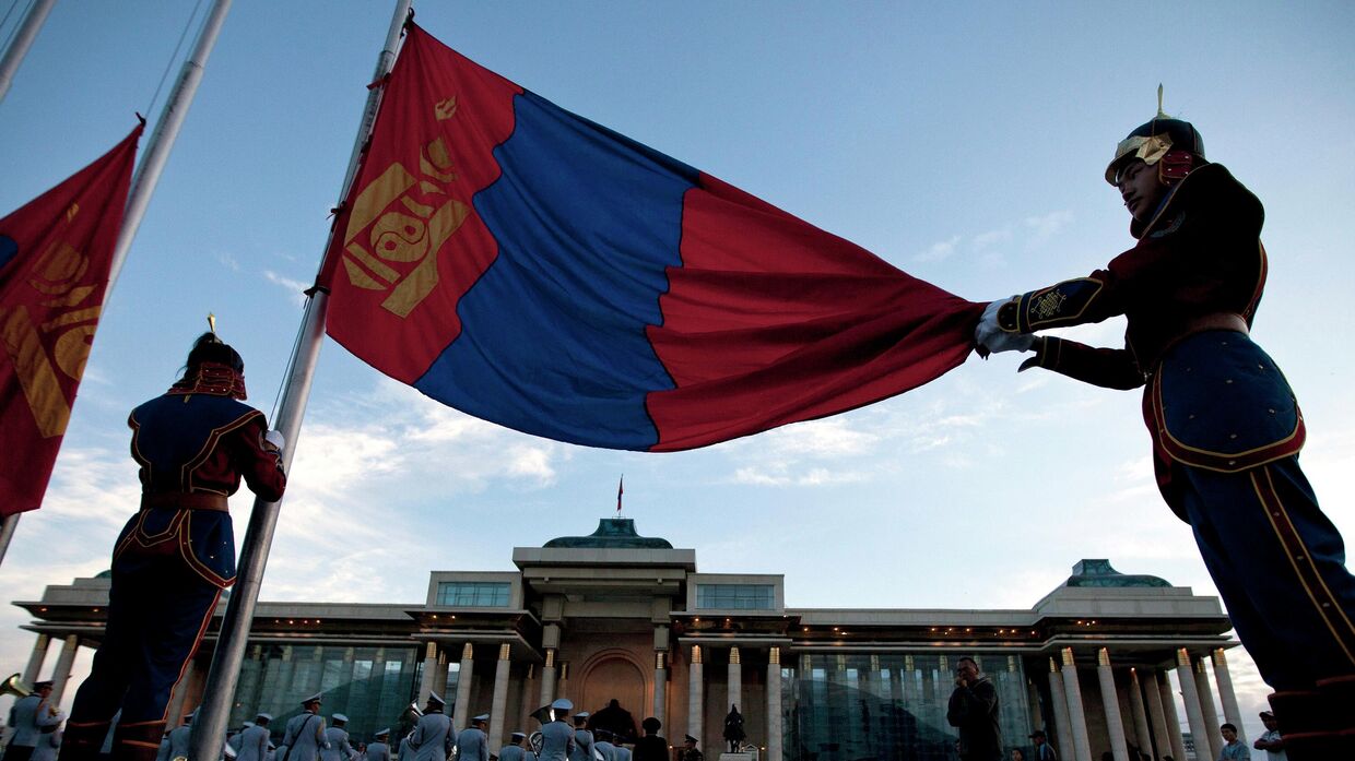 Флаг Монголии перед зданием парламента на площади Сухэ-Батора в Улан-Баторе