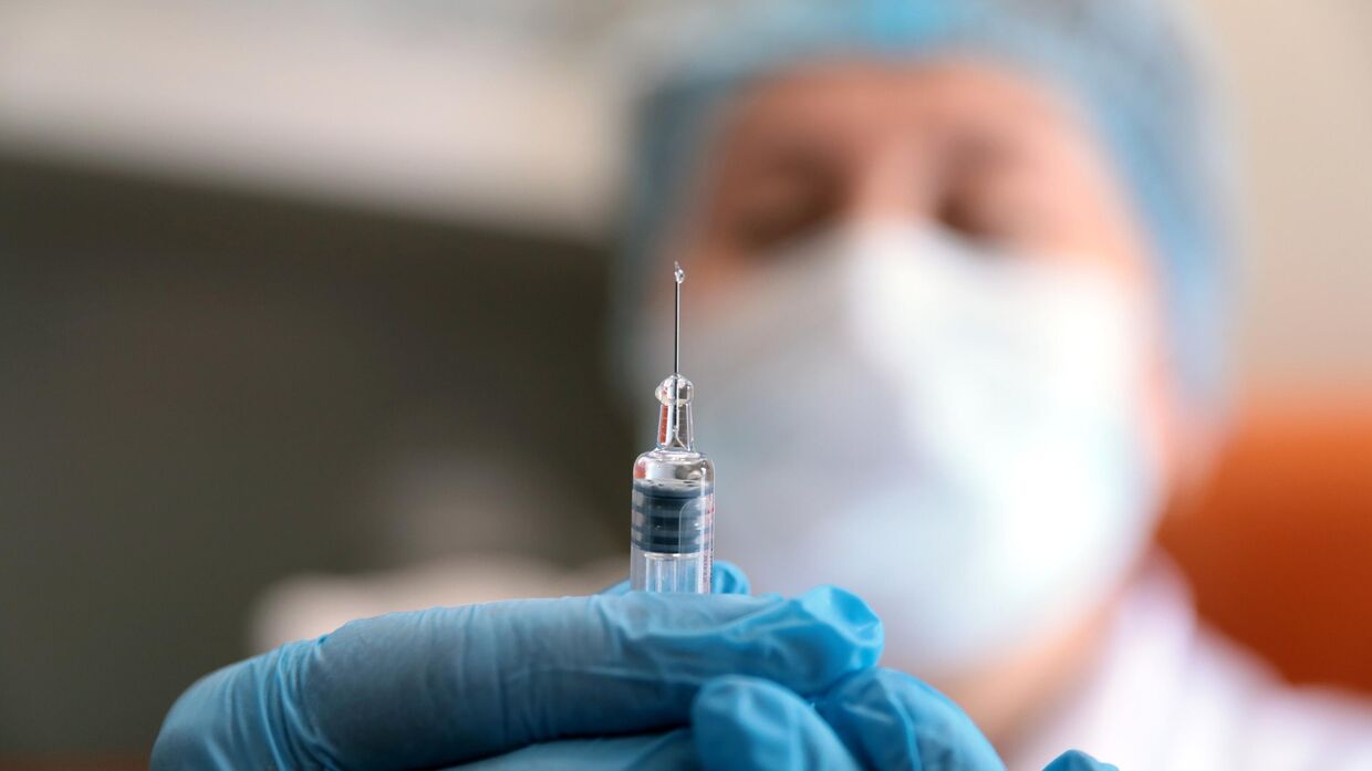 Медик готовит шприц с вакциной против гриппа в мобильном пункте вакцинации на Пушкинской площади в Москве