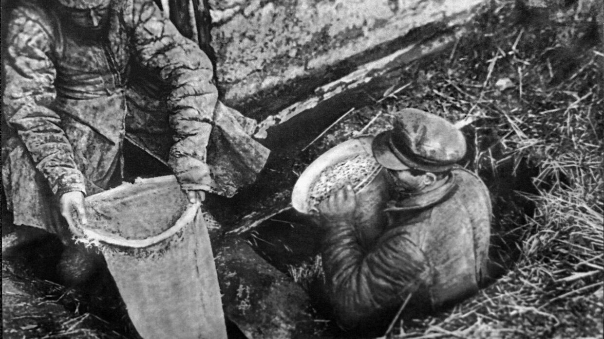 Работники ОГПУ извлекают из ямы спрятанное зерно. 1932 год