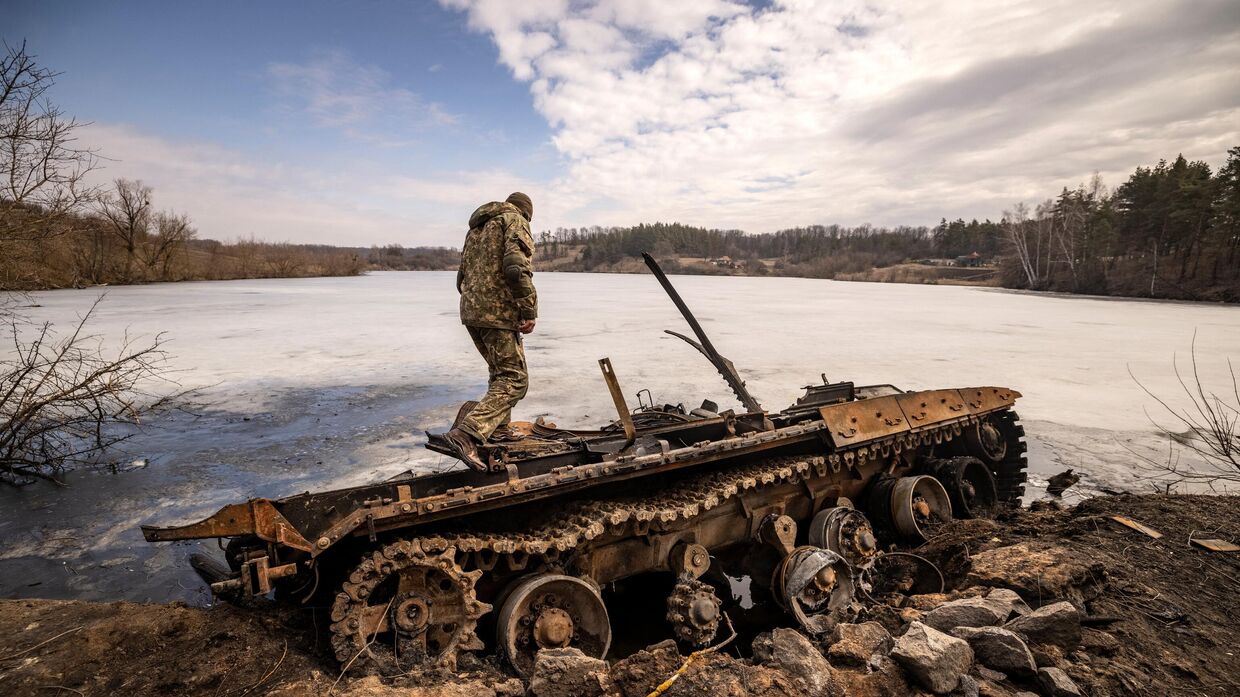 Украинский солдат осматривает уничтоженную технику. Архивная фотография
