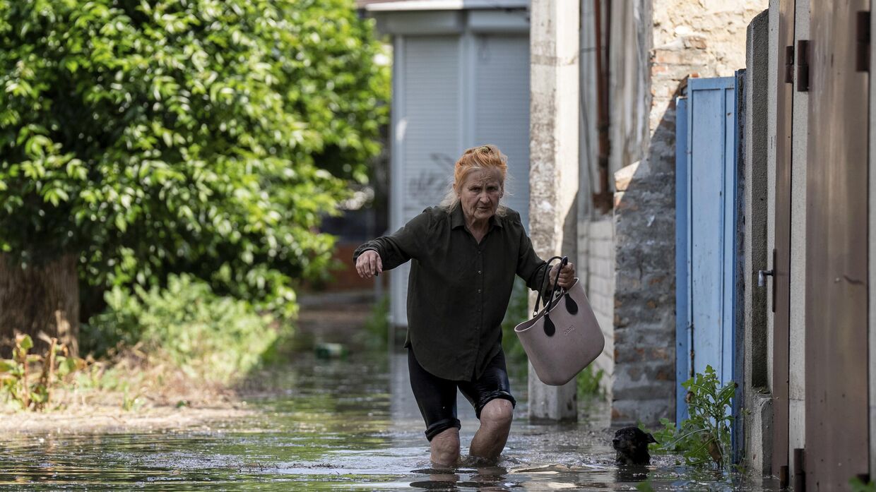 Местная жительница идет по затопленной дороге после того, как была обрушена плотина Каховской ГЭС в Херсоне, Украина, 6 июня 2023 года.