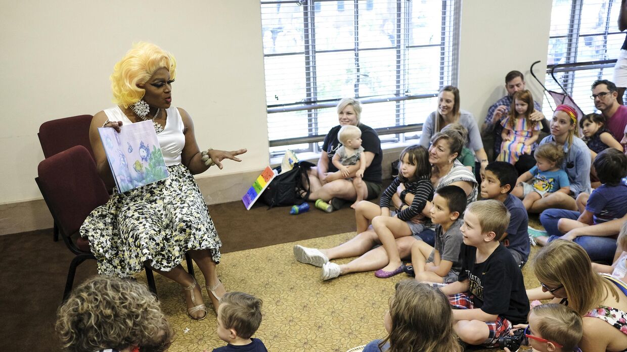 Трансвестит Шампань Монро читает книгу Радужная рыбка группе детей и их родителям в публичной библиотеке в рамках мероприятия Час истории трансвеститов в городе Мобил, штат Алабама, 8 сентября 2018 года.