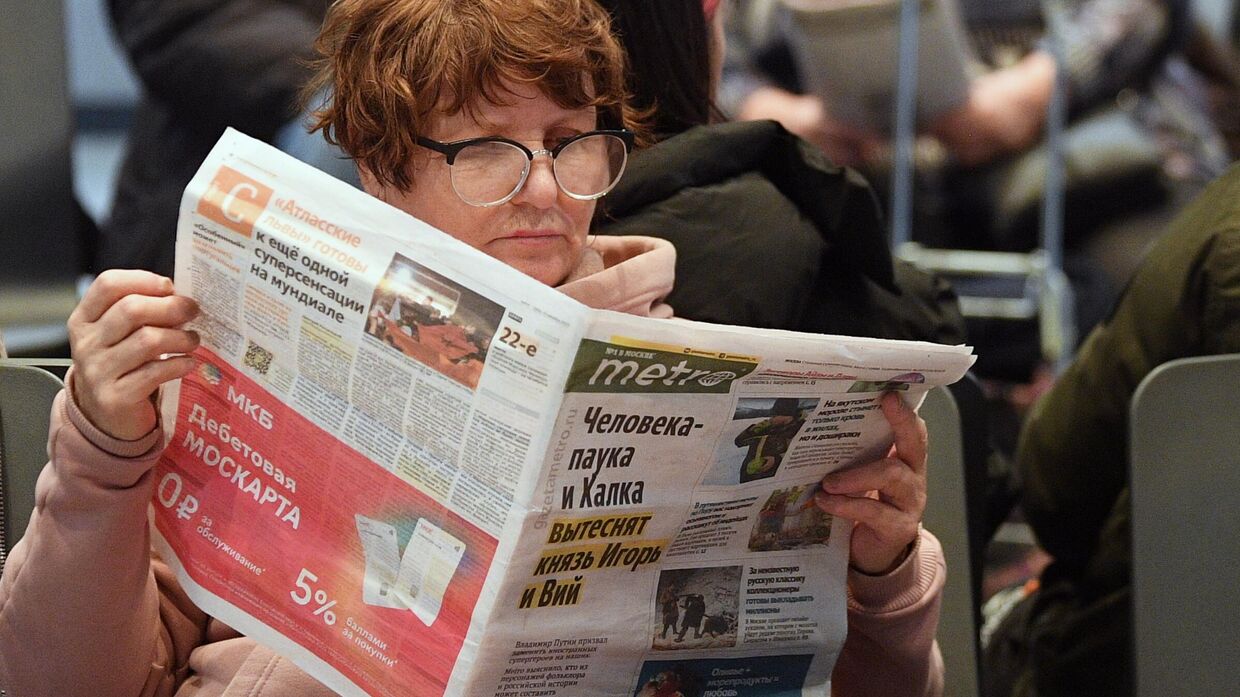 Пассажирка читает газету в зале ожидания на автовокзале Саларьево.