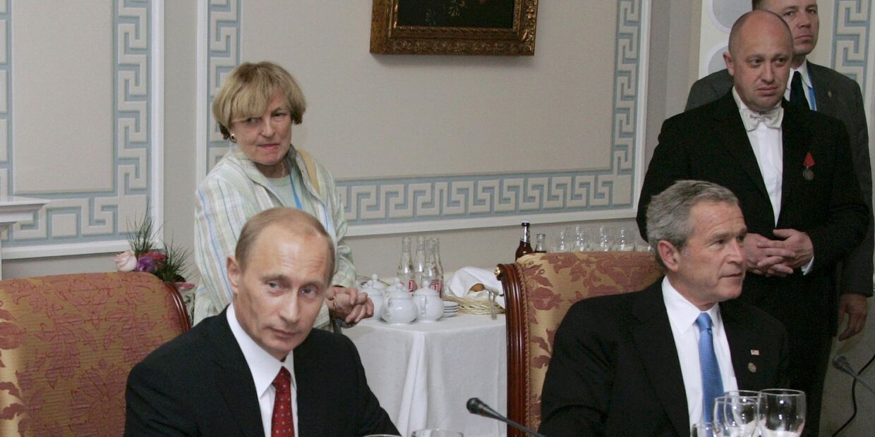 Президент России Владимир Путин и президент США Джордж Буш-младший принимают участие в рабочем ужине с другими лидерами стран Большой восьмерки, российский бизнесмен Евгений Пригожин стоит справа. Санкт-Петербург, Россия. 19 июля 2006 года
