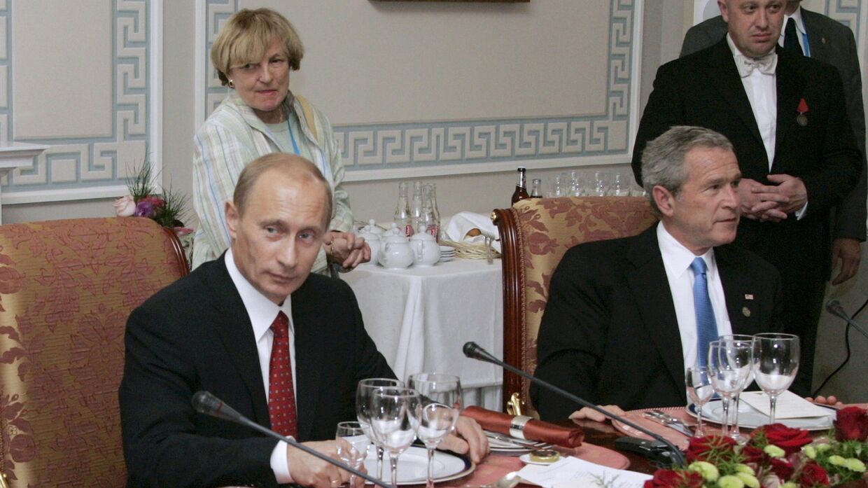 Президент России Владимир Путин и президент США Джордж Буш-младший принимают участие в рабочем ужине с другими лидерами стран Большой восьмерки, российский бизнесмен Евгений Пригожин стоит справа. Санкт-Петербург, Россия. 19 июля 2006 года