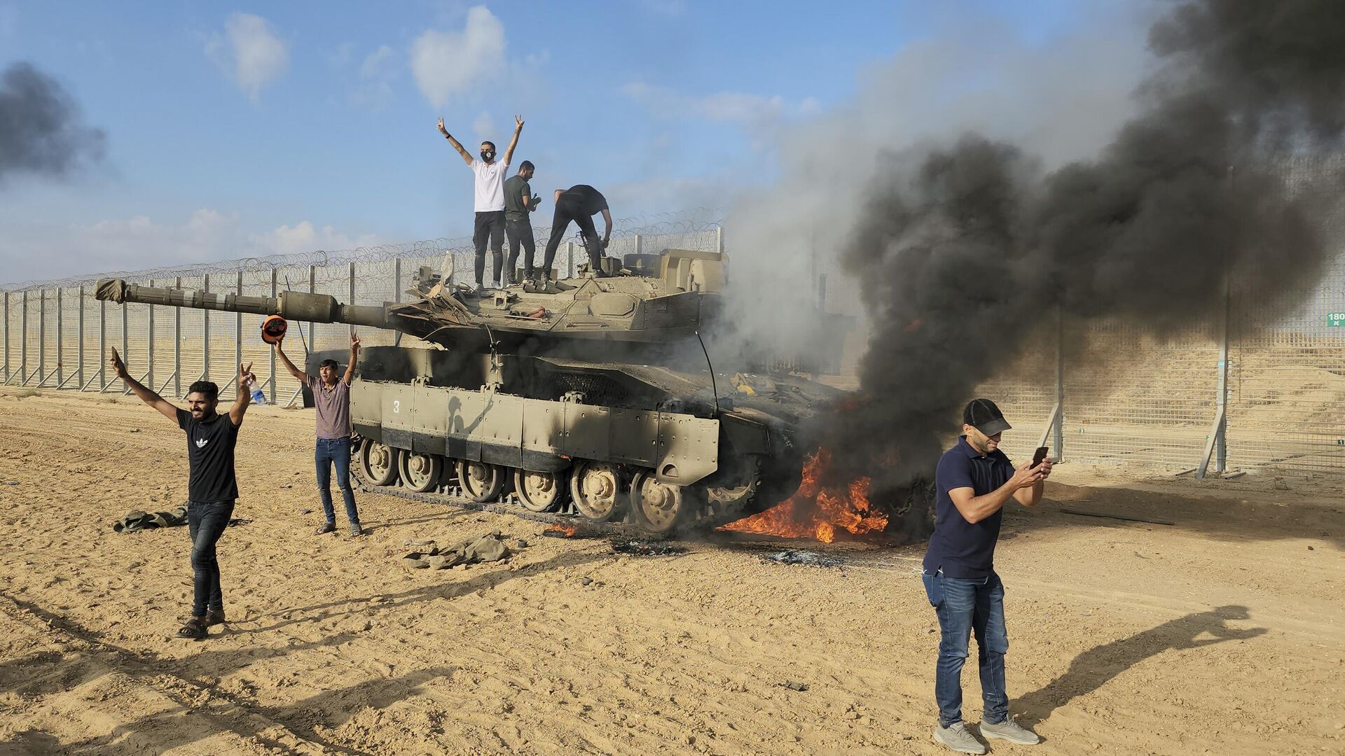 Палестинцы ликуют возле уничтоженного израильского танка рядом с ограждением сектора Газа  в субботу, 7 октября 2023 года - ИноСМИ, 1920, 01.11.2023